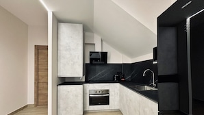 Eine moderne Küche mit Einbauofen, schwarzem Arbeitsplatz und einer Holztür.