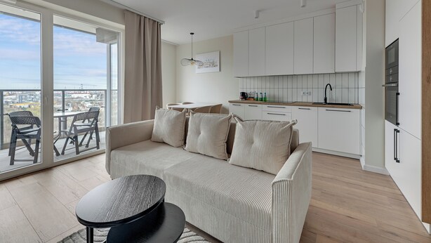 A modern apartment with a balcony, a sofa, a dining table, and a kitchen area. - Horizon 169 - SeaView by GrandApartments (Gdansk)