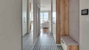 A modern hallway with a tiled floor, wooden accents, and a view to a living area. - Horizon 169 - SeaView by GrandApartments (Gdansk)
