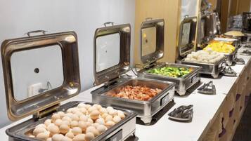 Un bufé con distintos alimentos en recipientes metálicos.