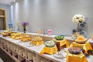 Disposición de bufé con diferentes platillos y un centro de mesa floral.