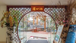 Entrada de hotel con puerta de cristal, un cartel sobre la puerta y felpudo de bienvenida.