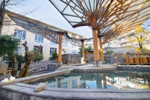 Uma área de piscina com estrutura de teto de vidro, degraus de pedra e reflexo de edifícios.