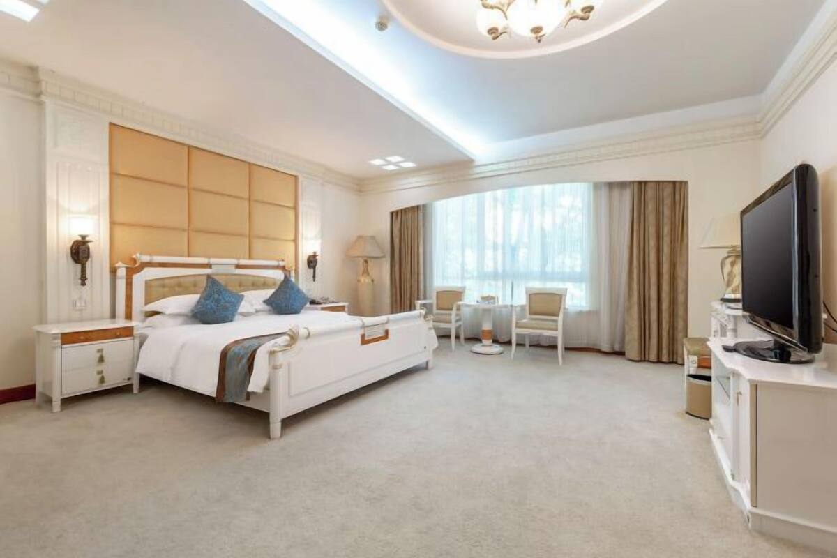 Een hotelkamer met een groot bed, een televisie, een bureau en een stoel.