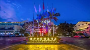 Entrada de hotel con exhibición de banderas y señalización iluminada.