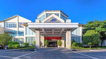 A modern building with a prominent entrance, a clear sky, and well-maintained landscaping.