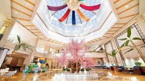 Un vestíbulo amplio con un arreglo floral central, un techo alto con diseño geométrico y una estética moderna y elegante.