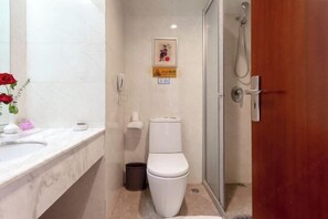 Une salle de bain équipée de toilettes, d’un lavabo, d’une poubelle et d’une douche.