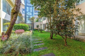 Un patio con un sendero empedrado, follaje y un edificio con amplios ventanales.