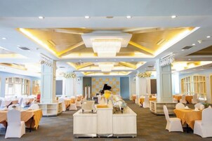 Un salón de banquetes con mesas redondas, una zona de bar central y una araña.