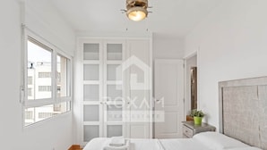 A bedroom with a bed, a nightstand, a window, and a door. - Ocean View Apartment (Platja de Gandia)