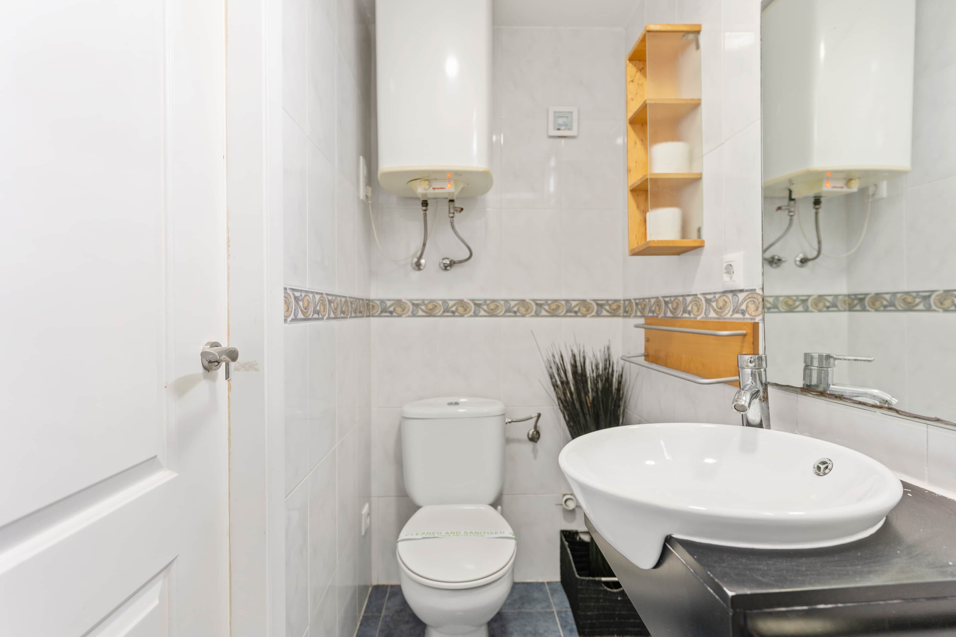 A bathroom with a white toilet, a sink with a mirror above it, and a shower area.