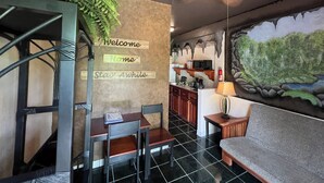 Ein Essbereich mit Tisch, Stühlen, einer Couch, einem Deckenventilator und einer Wand mit 'Welcome Home'-Schildern.