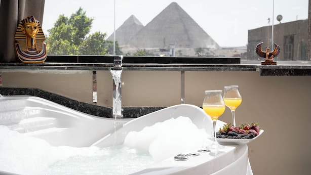 Eine Badewanne mit Blick auf Pyramiden, einer verzierten Kopfbedeckung und Obst auf einer Schale.
