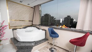 Ein modernes Badezimmer mit einer großen Badewanne, einem мраморному Waschtisch und einem Fenster mit Blick auf Palmen.