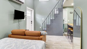 Une chambre avec un lit, une télévision, un climatiseur, un escalier et un coin cuisine.