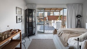 Een moderne slaapkamer met een groot bed, een houten nachtkastje, een glazen deur naar een balkon en uitzicht op de stad.