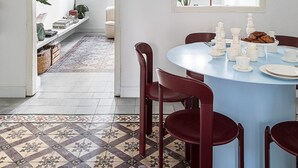 Een eethoek met een ronde tafel, rode stoelen en een vloer met een patroon.