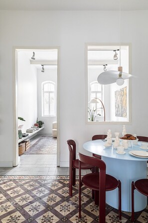 A dining area with a round table, red chairs, and a patterned floor. - Historic Beauty Blends with Modern Design (Tel Aviv-Yafo)