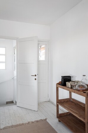 A white door with a keyhole, a wooden shelf with various items, and a white floor.