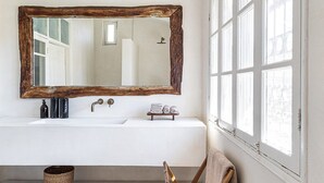 Een badkamer met een grote spiegel, twee wasbakken, een handdoekrek en een raam.
