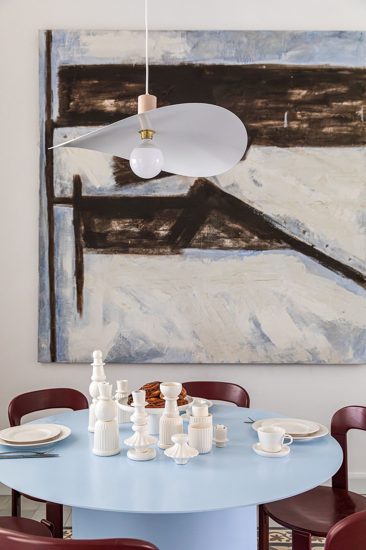 A dining area with a round table set for four, featuring white dinnerware and a centerpiece of candles.