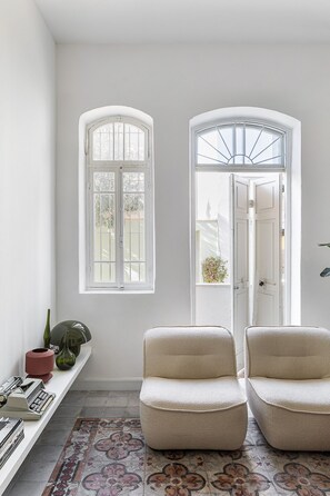 A room with two armchairs, a shelf with decorative items, and a patterned rug.