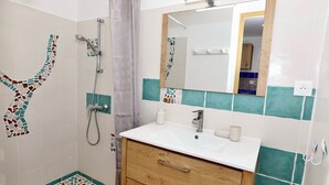 A bathroom with a shower, a sink, and a mirror.