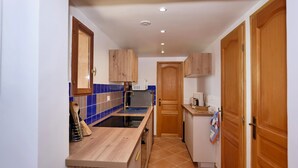 A compact kitchen with wooden cabinets, a blue-tiled backsplash, a sink, and a microwave.