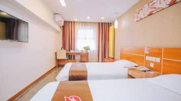 Quarto de hotel com duas camas, uma escrivaninha, uma cadeira, uma TV e uma janela com cortinas.