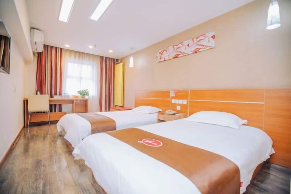 A hotel room with two beds, a desk, and a chair.