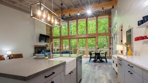 A modern kitchen with a large island, wooden beams, and a view of the outdoors.