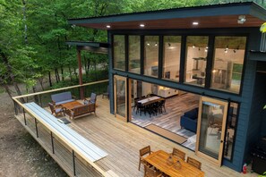 Ein modernes Haus mit einer Terrasse, großen Fenstern und einem Essbereich.