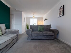 Relax in this inviting living room with a sofa, armchair, and greenery.