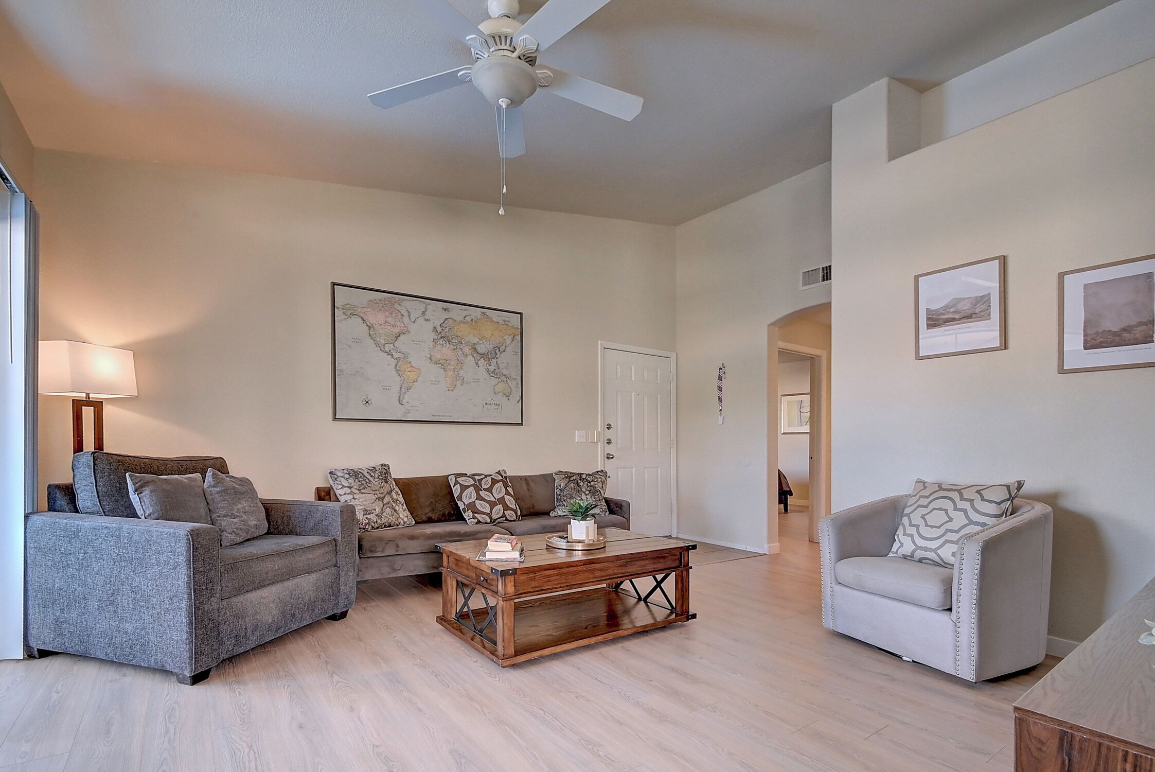 A living room with a sofa, armchair, coffee table, and a ceiling fan.