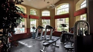 A gym with treadmills, a bench press, and a rowing machine, with large windows and a ceiling fan. - Scottsdale 3 Bdrm Condo w/Garage!  Great complex w/ Pool! (Scottsdale)