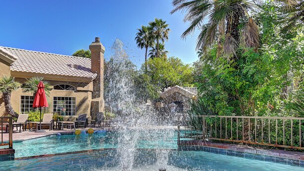 A pool with a water fountain, palm trees, and a building with a tiled roof. - Scottsdale 3 Bdrm Condo w/Garage!  Great complex w/ Pool! (Scottsdale)