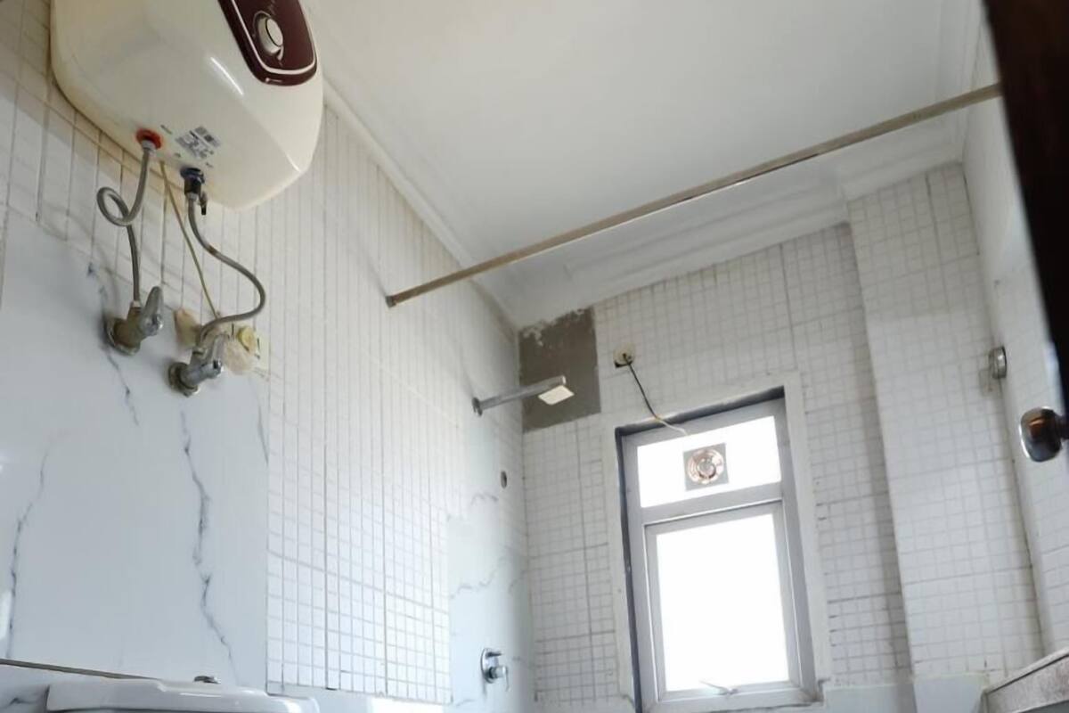A bathroom with a toilet, a shower, and a window.