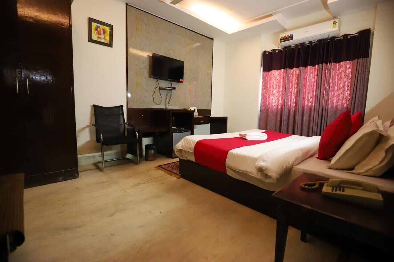 Una habitación de hotel con cama, escritorio, silla, televisor y teléfono.