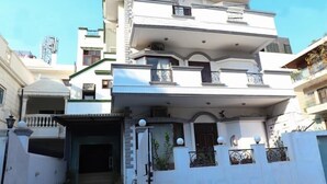 A multi-story residential building with a central entrance, balconies, and a gated driveway. - The Hotel Vagmi (Gurugram)