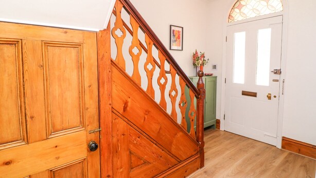A wooden staircase with a decorative railing leading to a white door with a glass window. - 4 South Park (Lincoln)