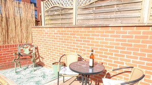 A patio with a brick wall, wicker chairs, a table, and a bottle of wine. - 4 South Park (Lincoln)