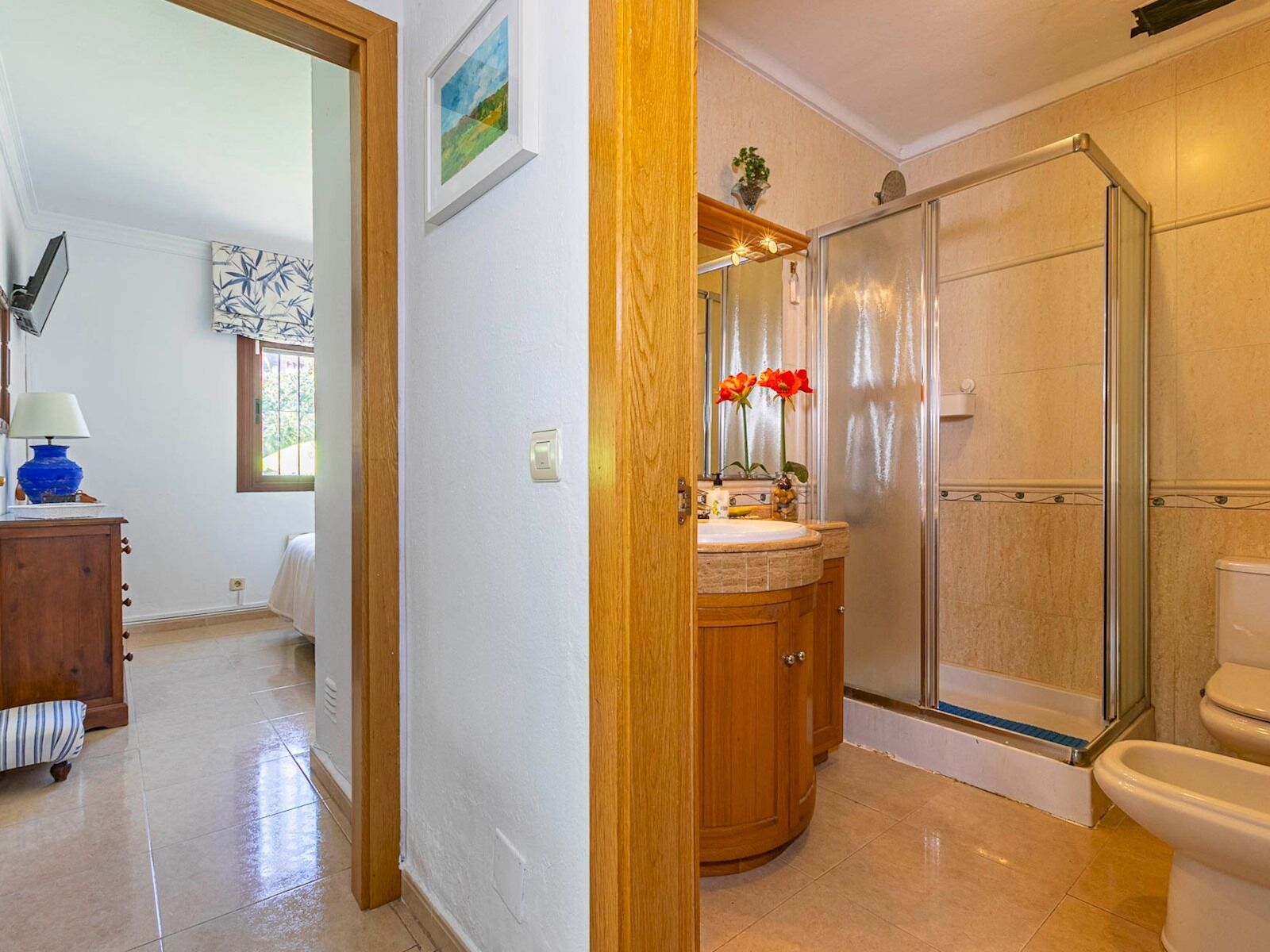 A bathroom with a glass shower enclosure, a sink with a mirror, and a toilet.