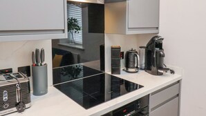 A modern kitchen with a black induction cooktop, a kettle, a coffee maker, and a toaster. - The Salisbury Sleeps 4 Classic Apartment (Scarborough)