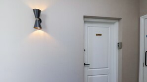 A white door with a brass plate, a wall-mounted light fixture, and a doorbell. - The Salisbury Sleeps 4 Classic Apartment (Scarborough)