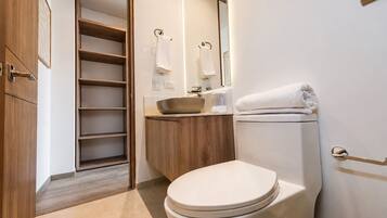 A modern bathroom with a toilet, sink, and built-in shelving.