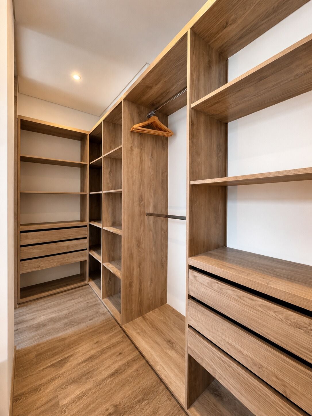 A walk-in closet with wooden shelving and a hanging rod.