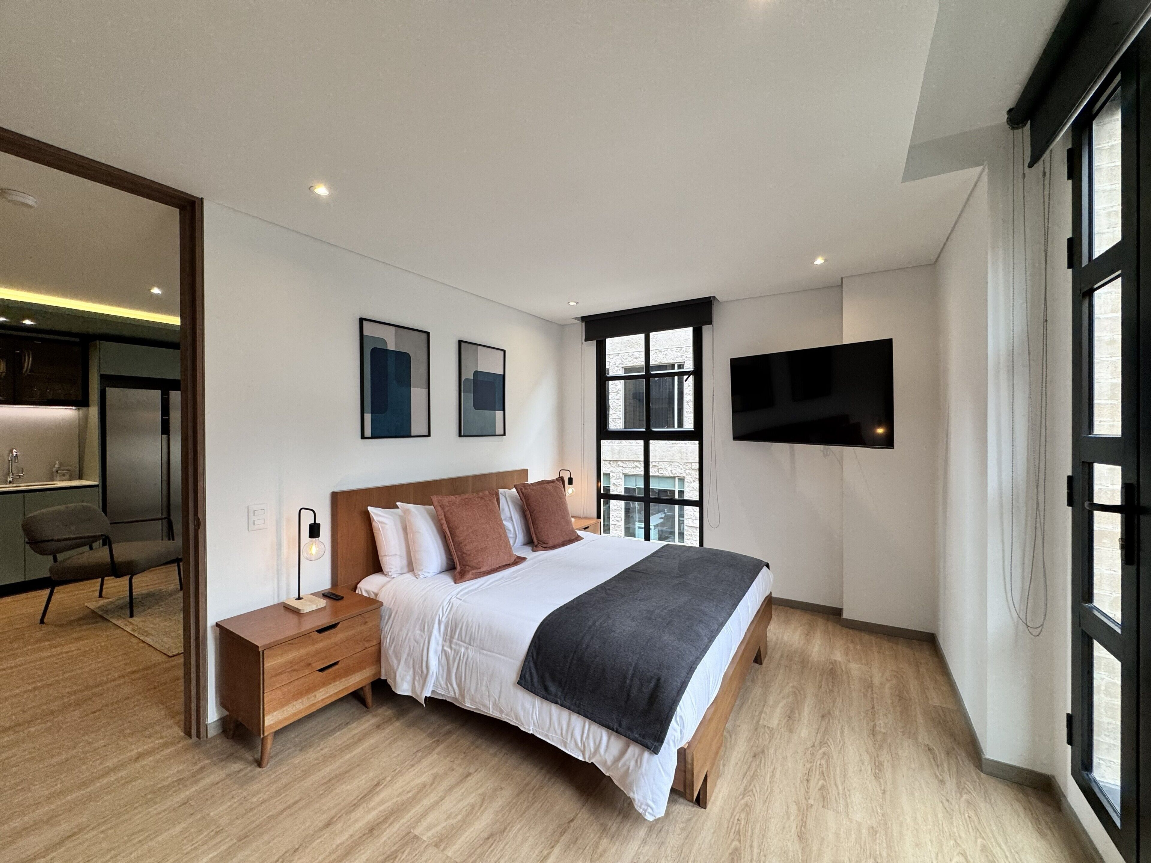 Une chambre moderne avec un lit, des tables de chevet, un bureau et un téléviseur.