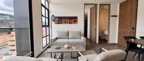 A modern living room with a sofa, two armchairs, a coffee table, and a cityscape painting.