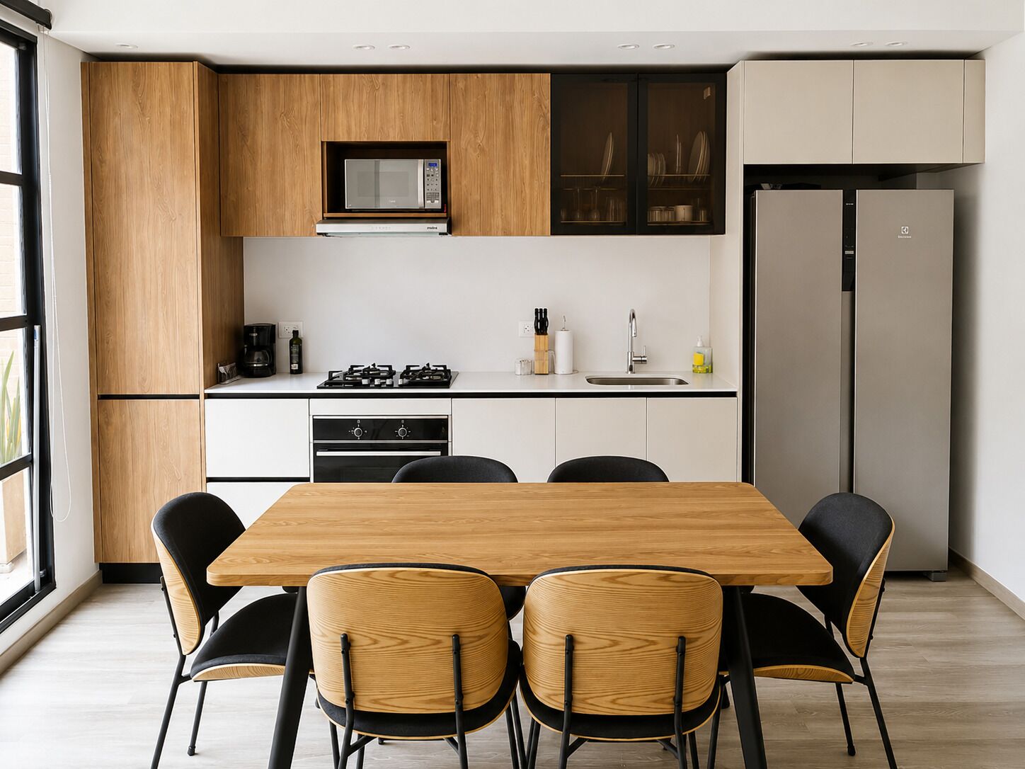 A modern kitchen with a dining table and chairs, a built-in microwave, and a refrigerator.